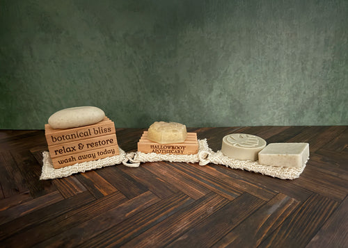 Four soap bars on a wooden surface with a textured green wall background